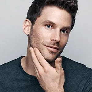 Mann berührt sein frisch rasiertes Gesicht, um die Glätte zu demonstrieren.