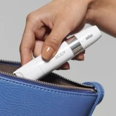 Braun Mini-Haarentferner wird in eine kleine blaue Handtasche gesteckt, um die Kompaktheit für unterwegs zu demonstrieren.
