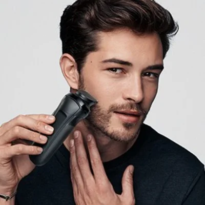 Braun Rasierer im Einsatz, ein Mann rasiert sich mit dem schwarzen Gerät den Bart.