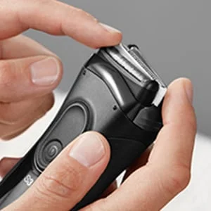 Braun Rasierer, Nahaufnahme der Scherkopfkassette, die von einer Hand berührt wird.