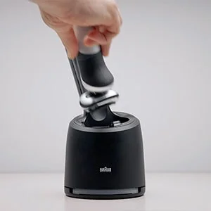 Braun Rasierer wird in eine Reinigungs- und Ladestation eingesetzt.