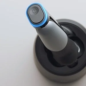 Braun Produkt auf einer Reinigungsstation mit blauem Licht um den Einschaltknopf herum.