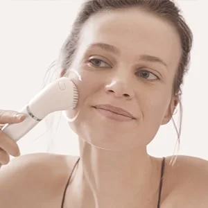 Frau benutzt eine Braun Gesichtsbürste und reinigt damit ihr Gesicht.