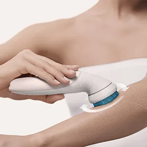 Braun Gesichtsbürste in Verwendung, die eine sanfte Exfoliation der Haut am Arm demonstriert.
