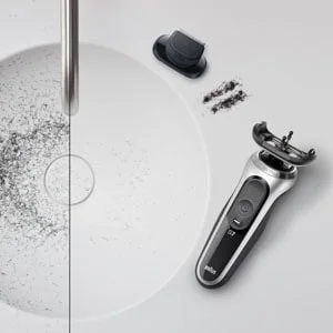 Braun Rasierer zur Reinigung zerlegt neben einem Waschbecken mit abgeschnittenen Barthaaren.